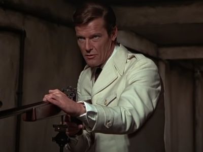 Roger Moore is wearing a white jacket as he is holding the gun.